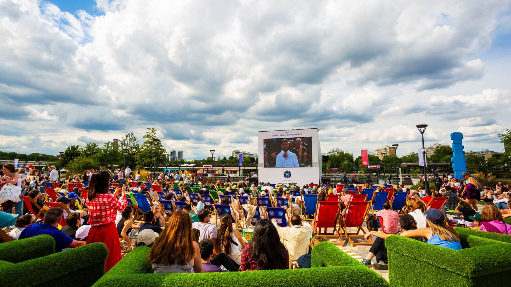 Crowds in deckchairs watching the big screen at the Wimbledon Experience fan village at Battersea in 2024